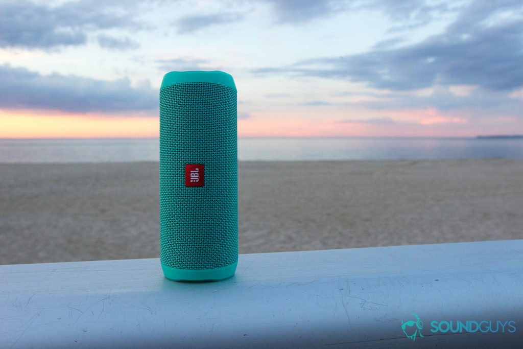 The mint colored JBL Flip 4 pictured against the sunset at the beach. 
