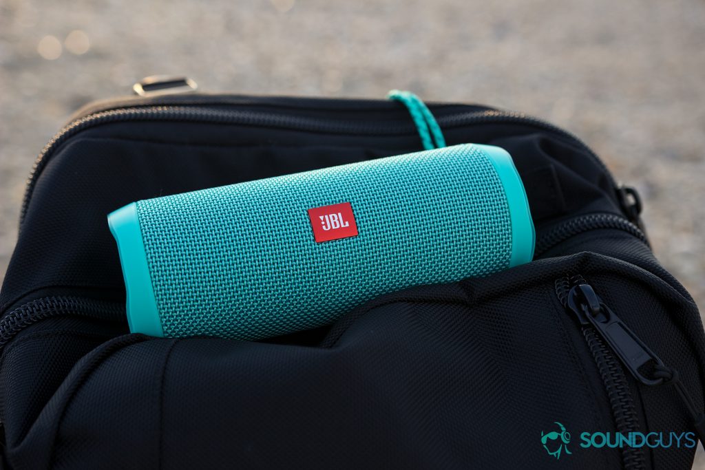 The teal JBL Flip 4 pictured on top of a black backpack. 