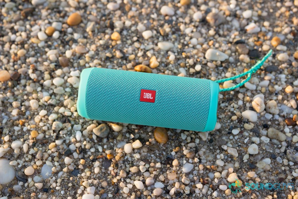 The teal JBL Flip 4 pictured on a rocky beach. 