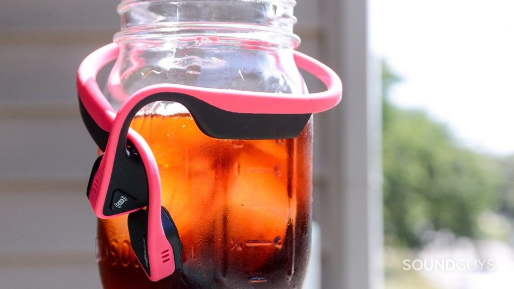 The headphones gently wrap around your head making and feel like a cozy hug. Pictured: The Aftershockz Trekz Titanium wrapped around a cold brew coffee. These are the safest Bluetooth headphones for running.