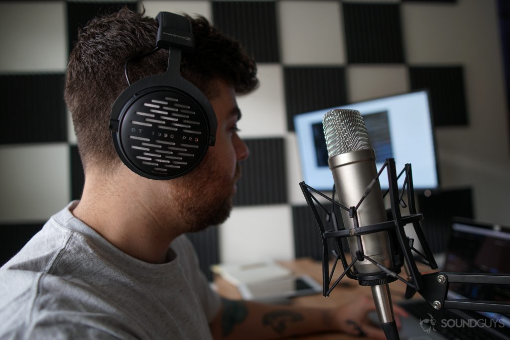Man wearing Beyerdynamic headphones while using the Rode NT1-A microphone with foam padding on the wall in the background. 
