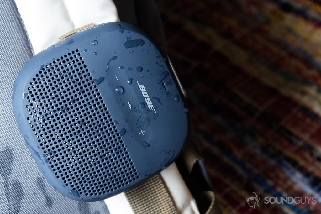 A picture of the Bose SoundLink Micro (blue) waterproof speakers hooked onto a white backpack.
