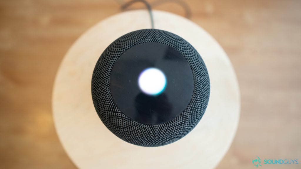 An aerial view of the Apple Homepod in black on a circular table.