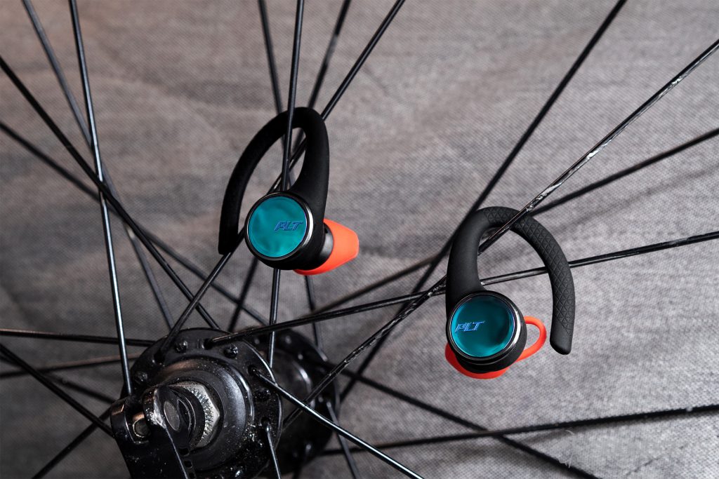A picture of the Plantronics BackBeat Fit 3100 earbuds hanging from the spokes of a road bike wheel.
