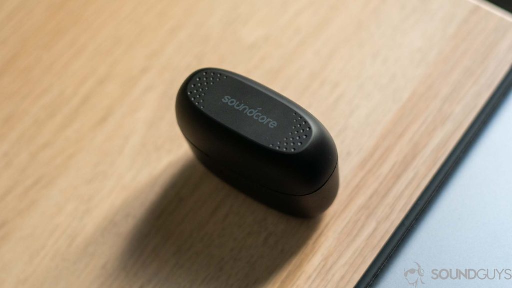 Pictured is the Anker Soundcore charging case on top of a wooden desk with the Soundcore logo clearly visible. 
