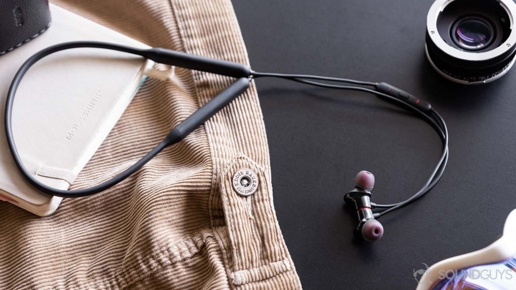 A picture of the OnePlus Bullets Wireless 2 earbuds and neckband resting on a journal/corduroy jacket.