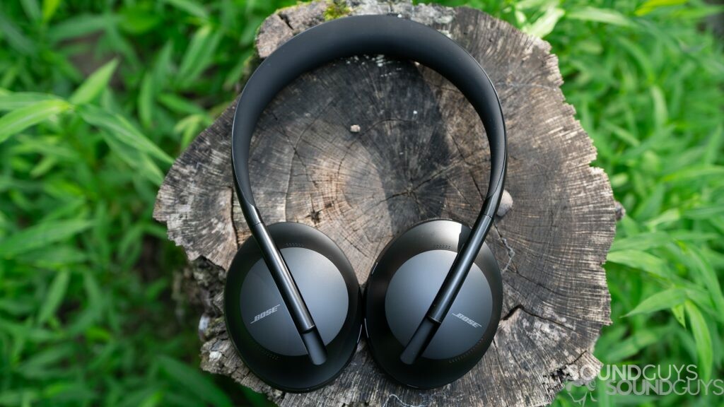 Bose Noise Cancelling Headphones 700 pictured from above on top of a tree stump with grass in the background. 