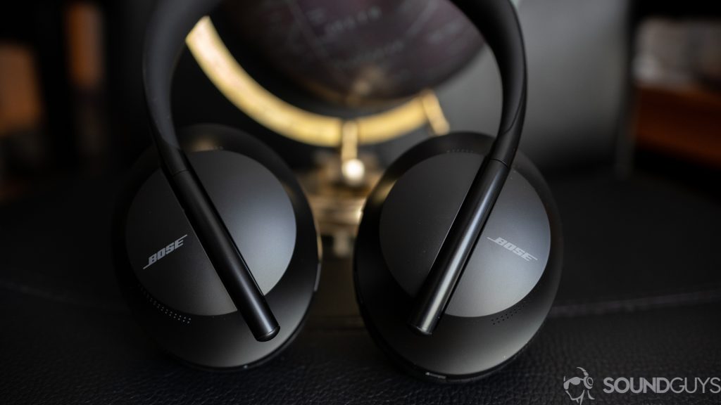 The Bose Noise Cancelling headphones 700 on a black surface resting against a globe.