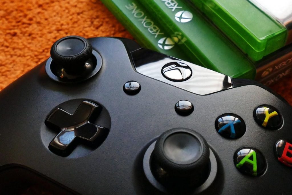 A photo of the Microsoft Xbox One controller resting near a stack of games - best xbox one headset