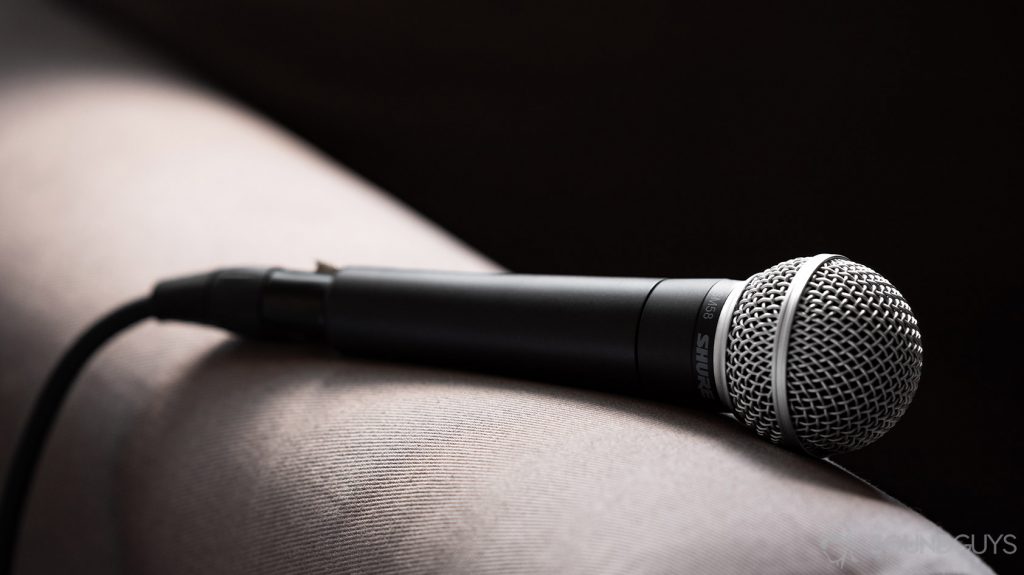 A photo of the Shure SM58 on the arm of a couch; this microphone is versatile and a great option for home studio recording.