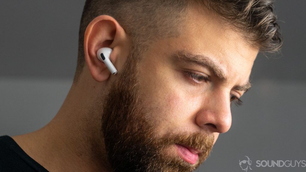 A picture of a man wearing the Apple AirPods Pro against a gray background.