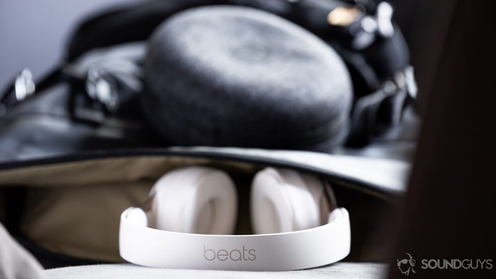 A photo of the Beats Solo Pro on-ear noise cancelling headphones headband emerging from a backpack with the cloth carrying pouch hooked to it.