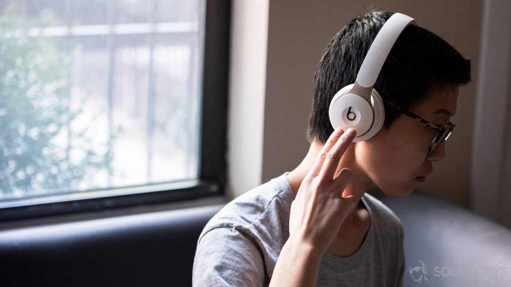 A photo of the Beats Solo Pro on-ear noise cancelling headphones being worn by a woman using the right ear cup controls.