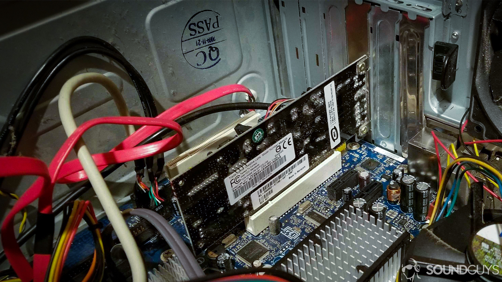 A photo of a soundcard installed in a PCI slot inside a dusty computer tower.