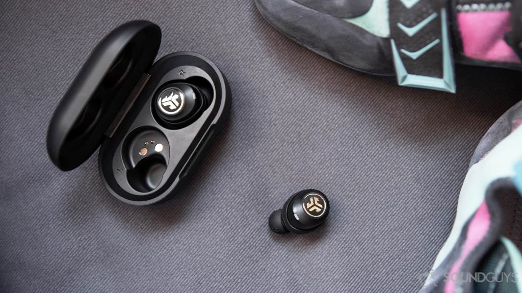 An aerial picture of the JLab JBuds Air Icon true wireless earbuds, one in the charging case and one out of it, next to rock climbing shoes.