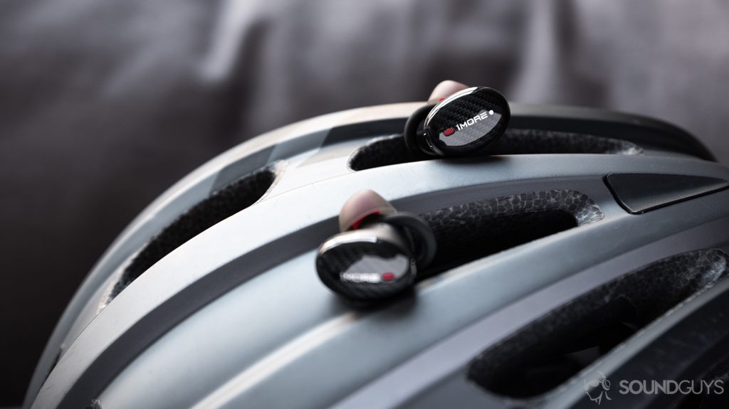 The 1More True Wireless ANC earbuds atop a grey bike helmet.
