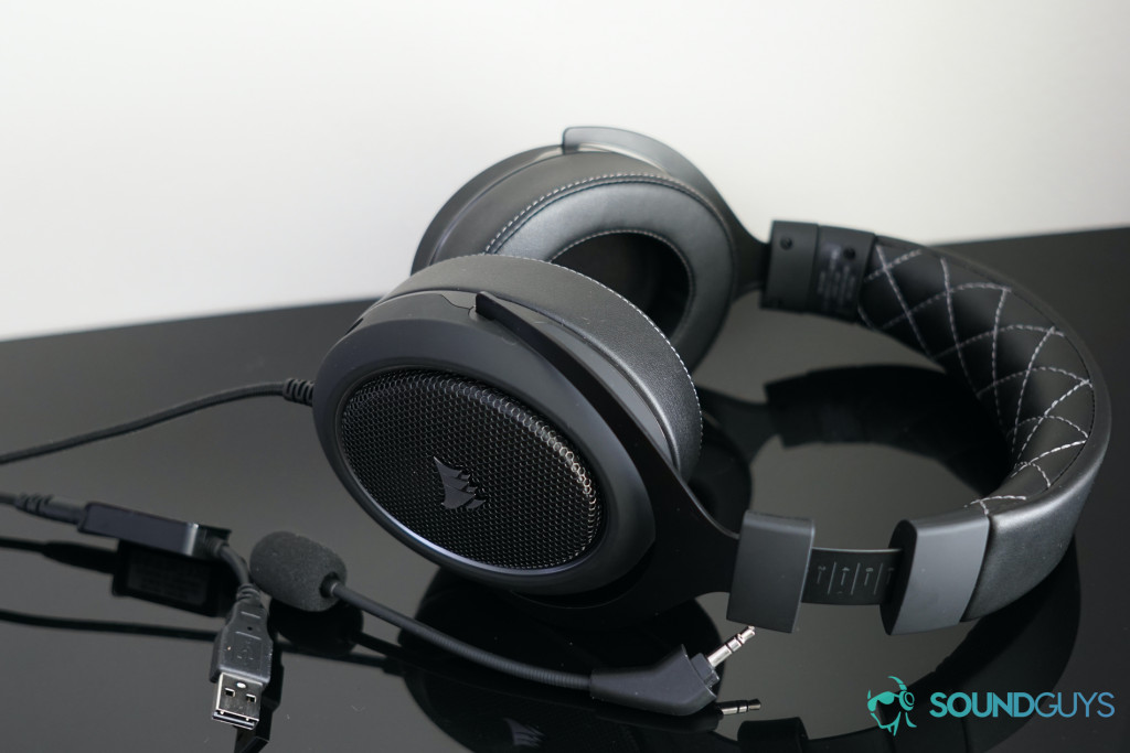 The Corsair HS60 Pro Surround lies next to its included microphone and USB adapter.