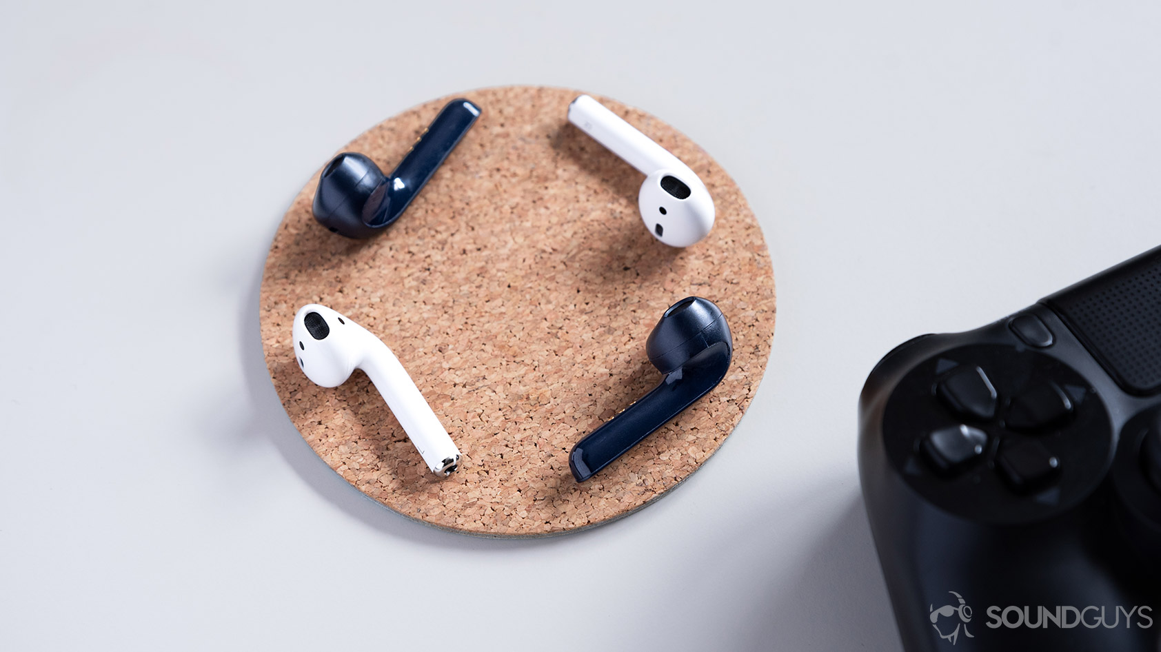 אוזניות אלחוטיות אמיתיות של Mobvoi TicPods 2 Pro לעומת Apple AirPods על תחתית שעם.