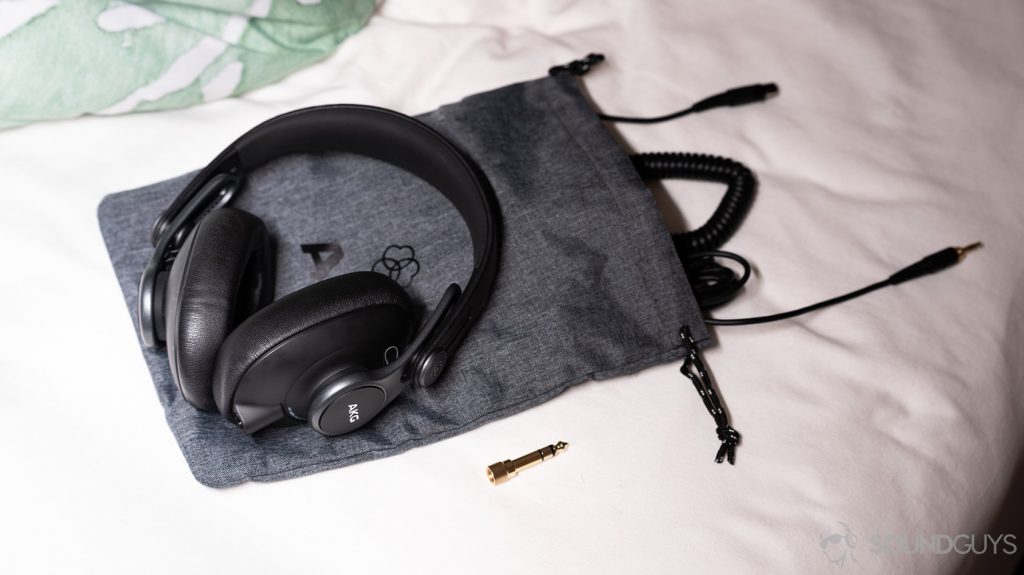A picture of the AKG K371 wired over-ear headphones on the included drawstring carrying pouch with the included cables.