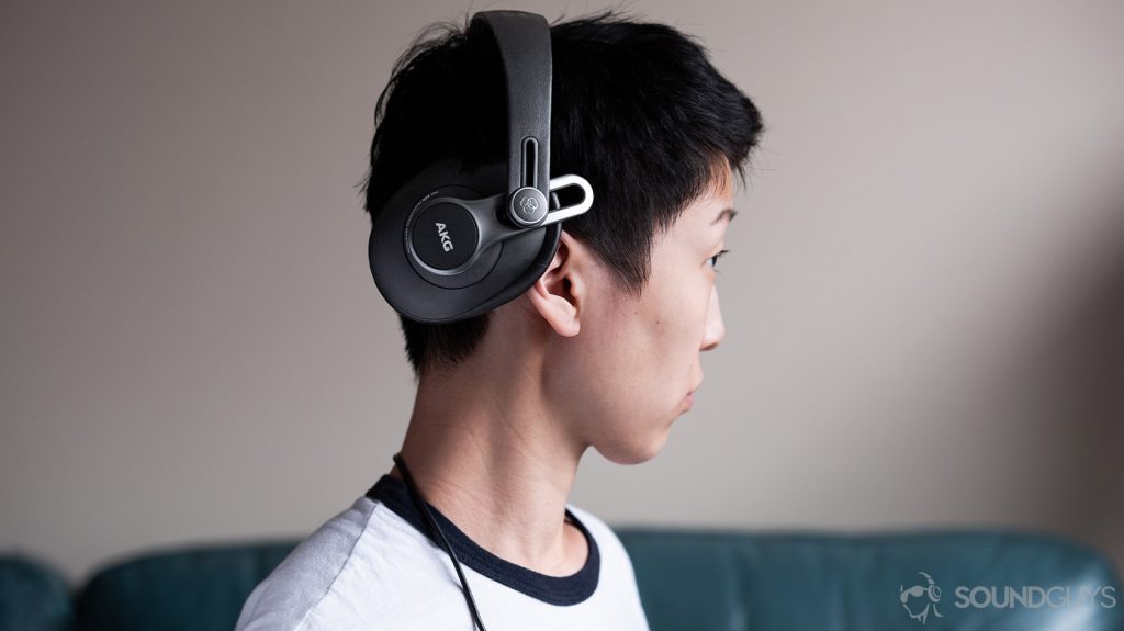 A picture of the AKG K371 wired over-ear headphones' ear cup rotated back 45 degrees while being worn by a woman in profile.