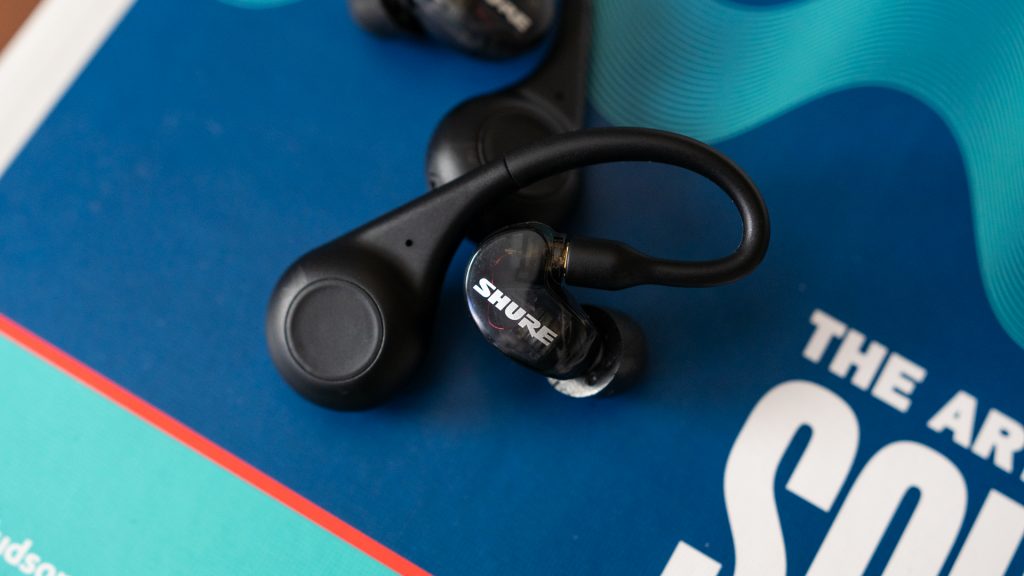The Shure Aonic 215 true wireless earbuds on top of a blue book