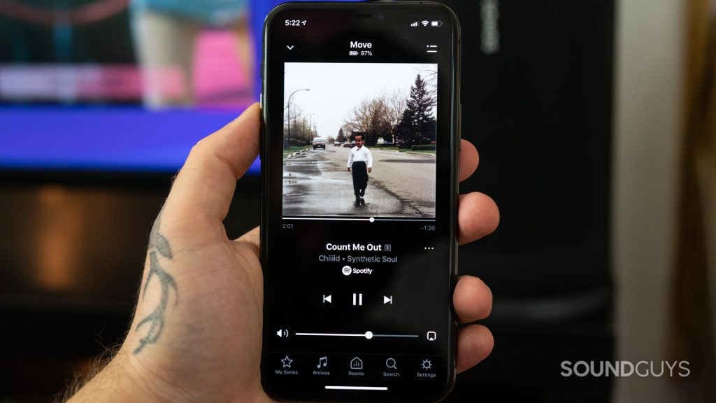Man holding iPhone 11 Pro with music playing in the Sonos app