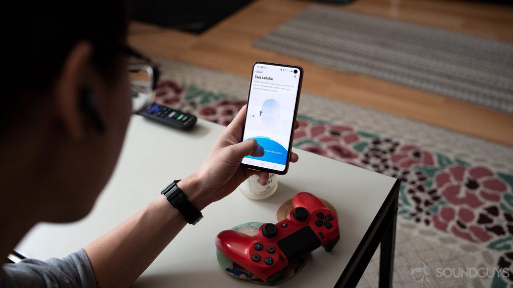 An aerial picture of the Anker SoundCore Liberty Air 2 true wireless earbuds being worn by a woman as she uses HearID to create a custom sound preset in the SoundCore mobile application on a Samsung Galaxy S10e.