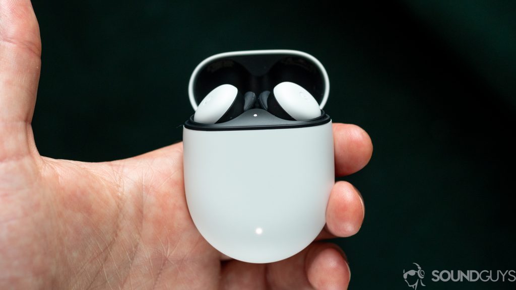 Man holding Pixel Buds charging case with the white Pixel Buds inside and the lid open