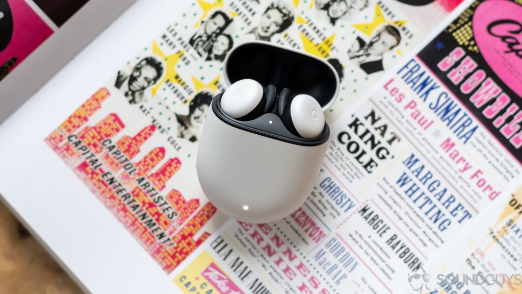 The new white Google Pixel Buds in the case against the colorful page of a book.