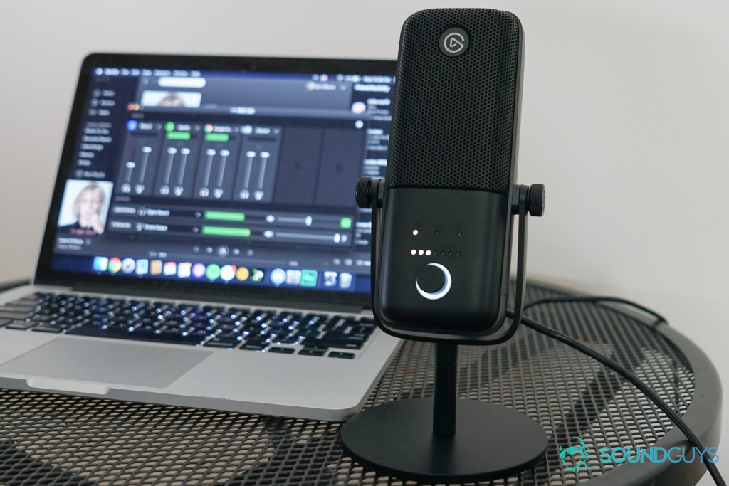 The Elgato Wave:3 Microphone sits on a metal table in front of a MacBook Pro.