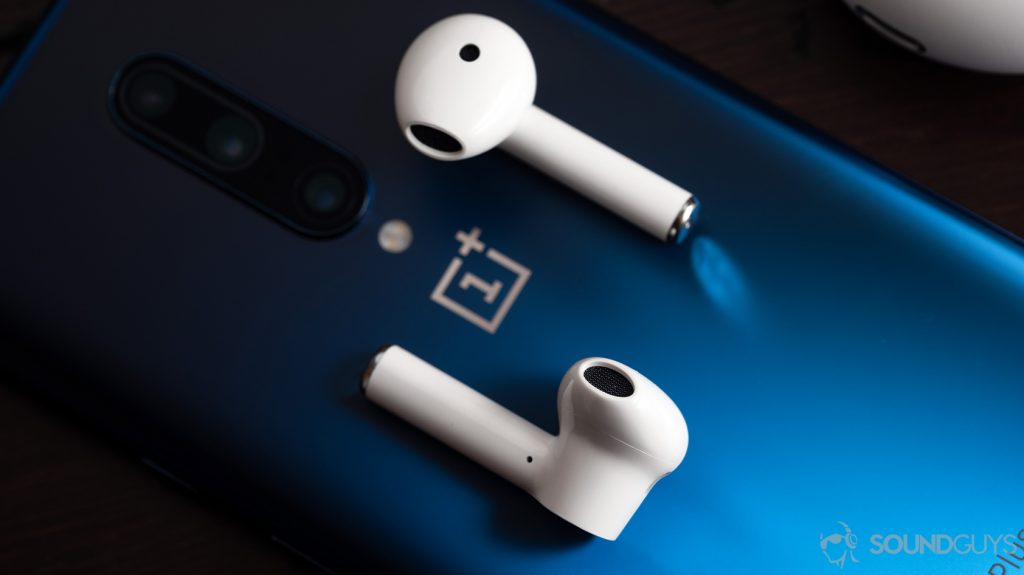 A picture of the OnePlus Buds true wireless earbuds (white) on top of a blue OnePlus 7 Pro smartphone.