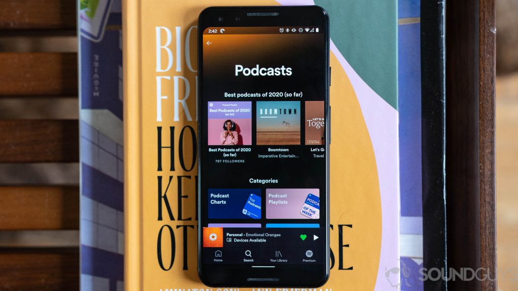 Pictured is Spotify podcasts screen on iPhone 11 Pro on top of books