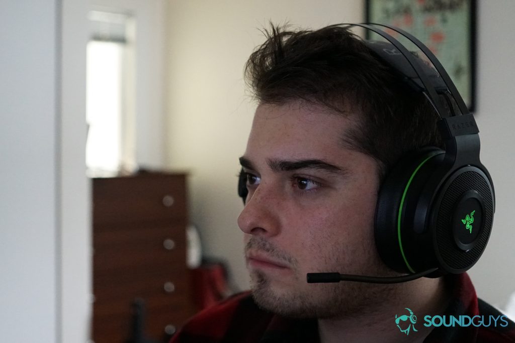A man wears the Razer Thresher Ultimate gaming headset seated at a desk.