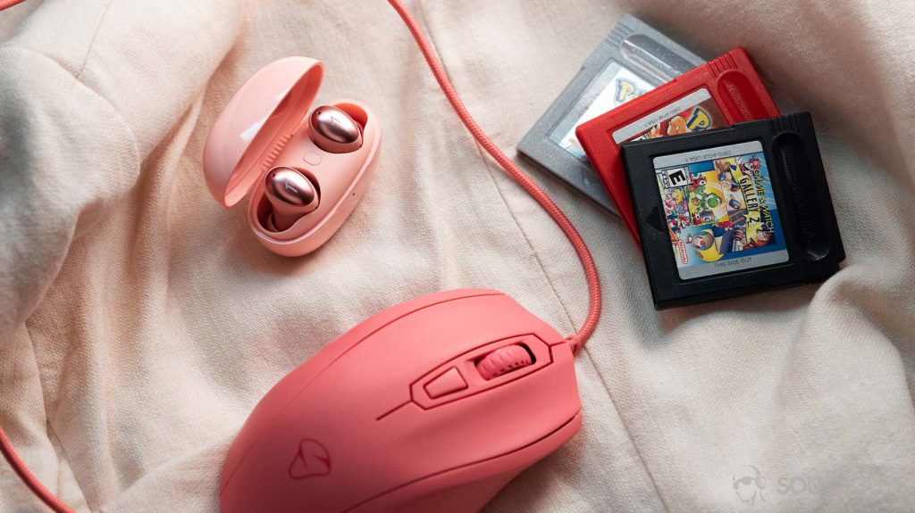 A picture of the 1MORE ColorBuds true wireless earbuds next to a pink wired mouse and set of three GameBoy game cartridges.