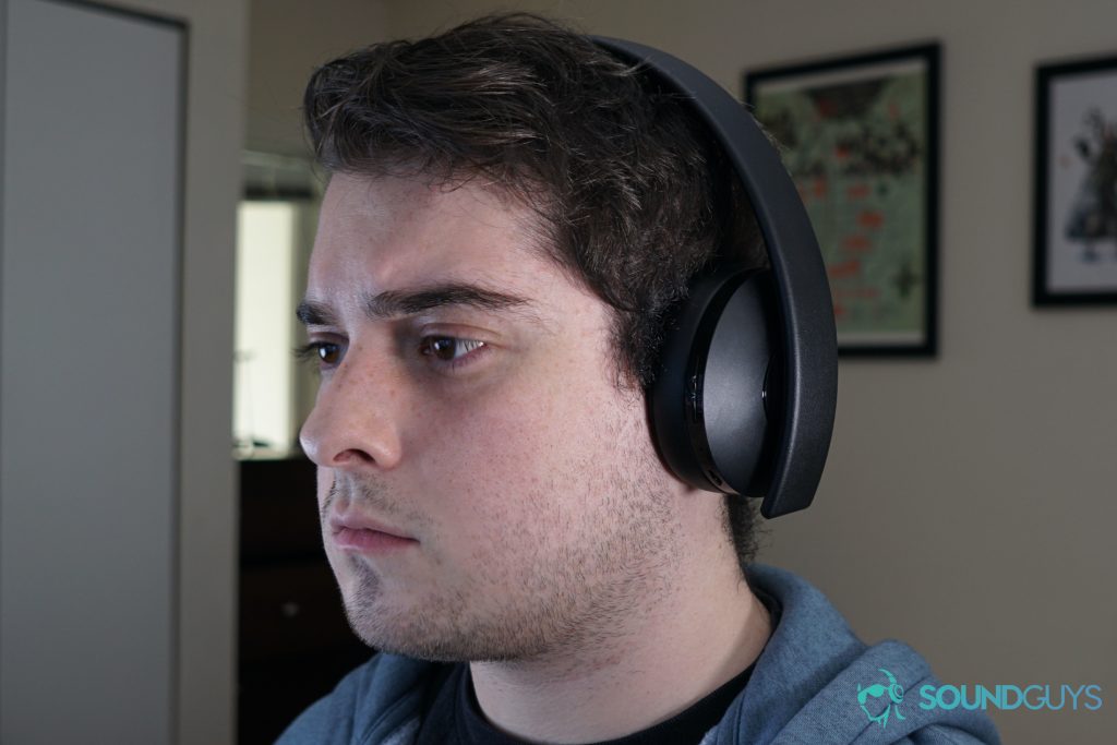 A man wears the Playstation Gold Wireless Headset with paintings on the wall behind him