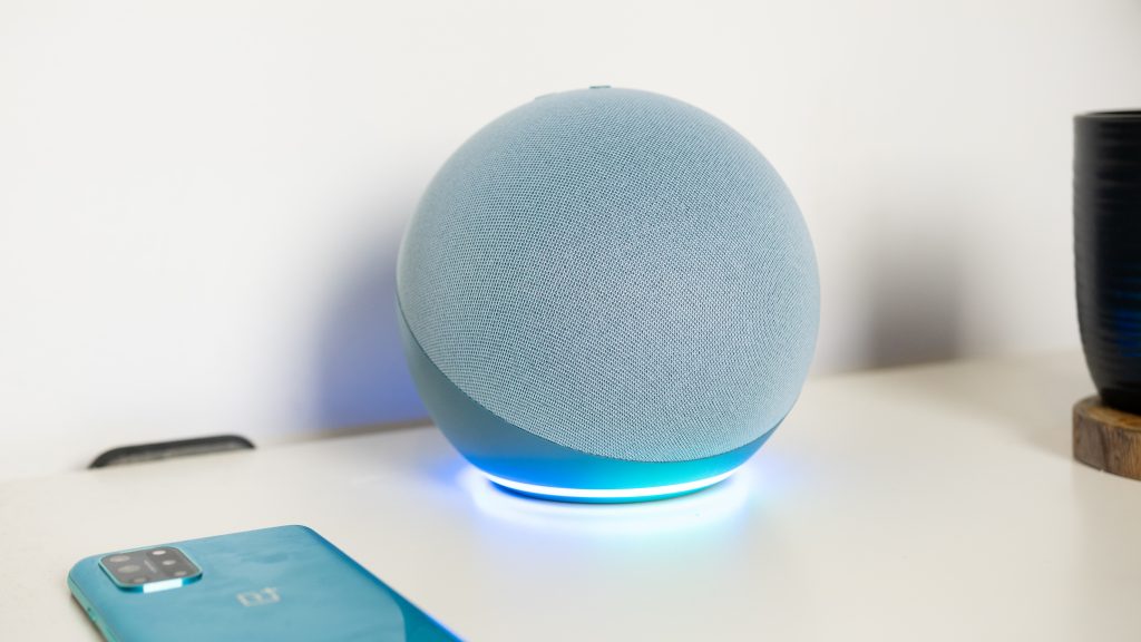 The Twilight blue Amazon Echo 4th gen with the LED light glowing blue on a white desk. 