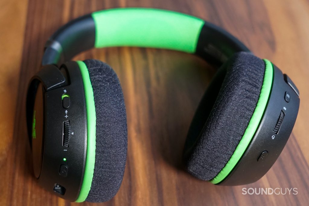 The Razer Kaira Pro lays on a wooden table with its on-ear controls on display.