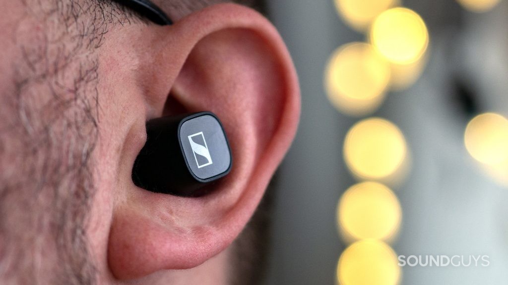 A photo showing the Sennheiser CX 400BT in a man's ear, with fairy lights in the background.