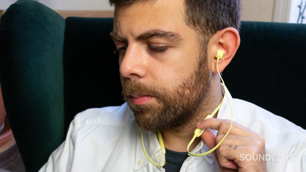 Man pressing button on Beats Flex earbuds.