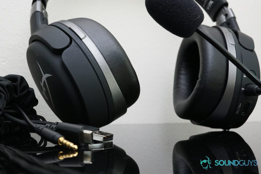 The HyperX Cloud Orbit S gaming headset sits on a reflective black surface next to its included cords.