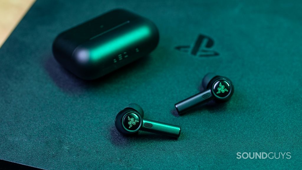 The Razer Hammerhead True Wireless Pro earbuds sit atop a PlayStation 4 gaming console.