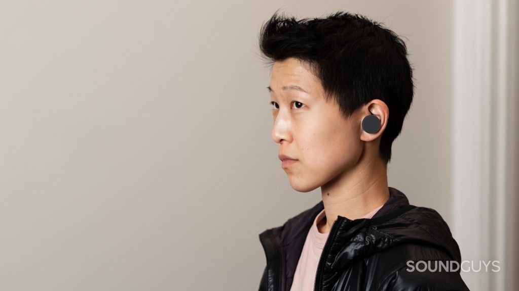 A woman wears the Microsoft Surface Buds true wireless earphones.
