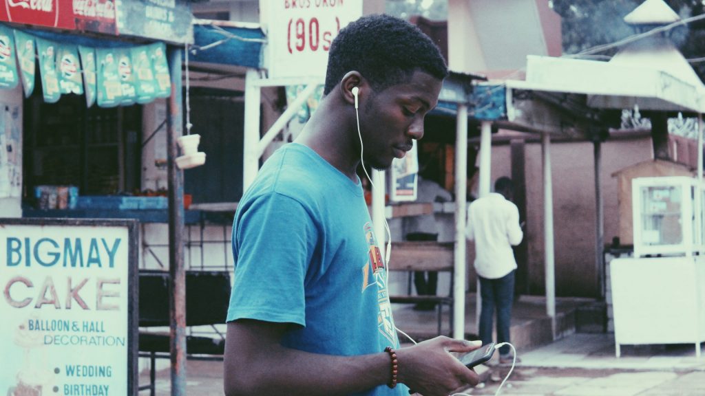 Man on the street using wired earbuds with a cellphone