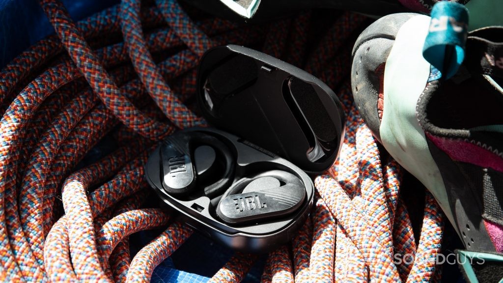 The JBL ENDURANCE PEAK II true wireless workout earbuds rest in the open charging case on top of a rock climbing rope.