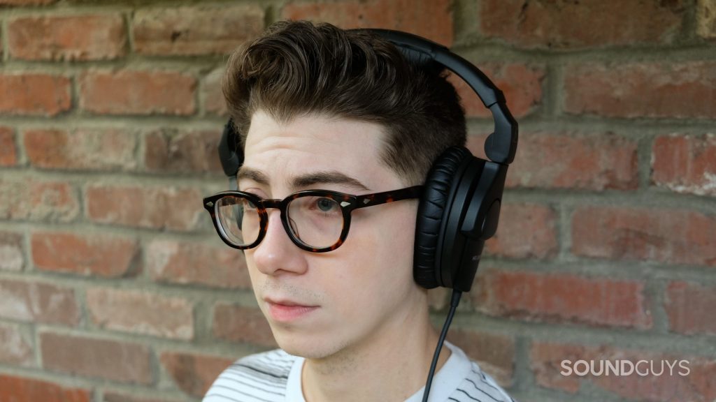 A man wears the Sennheiser HD 280 Pro studio headphones in front of a brick wall.