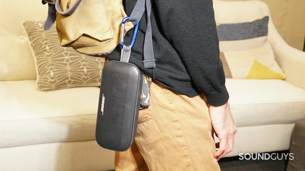 The Bose SoundLink Flex is hooked onto a person's backpack as they walk around a room.