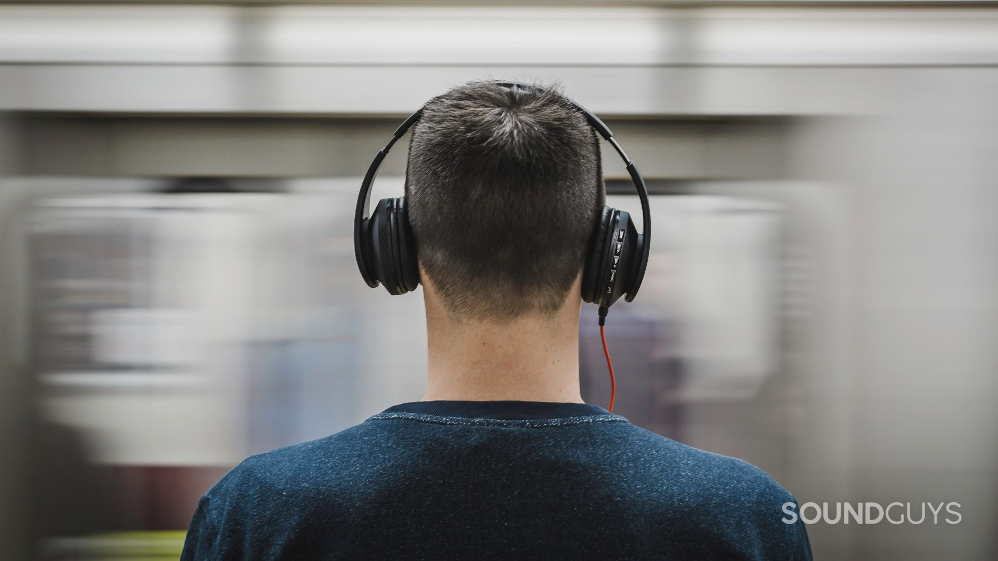A photo of a young man wearing headphones in front of a moving train