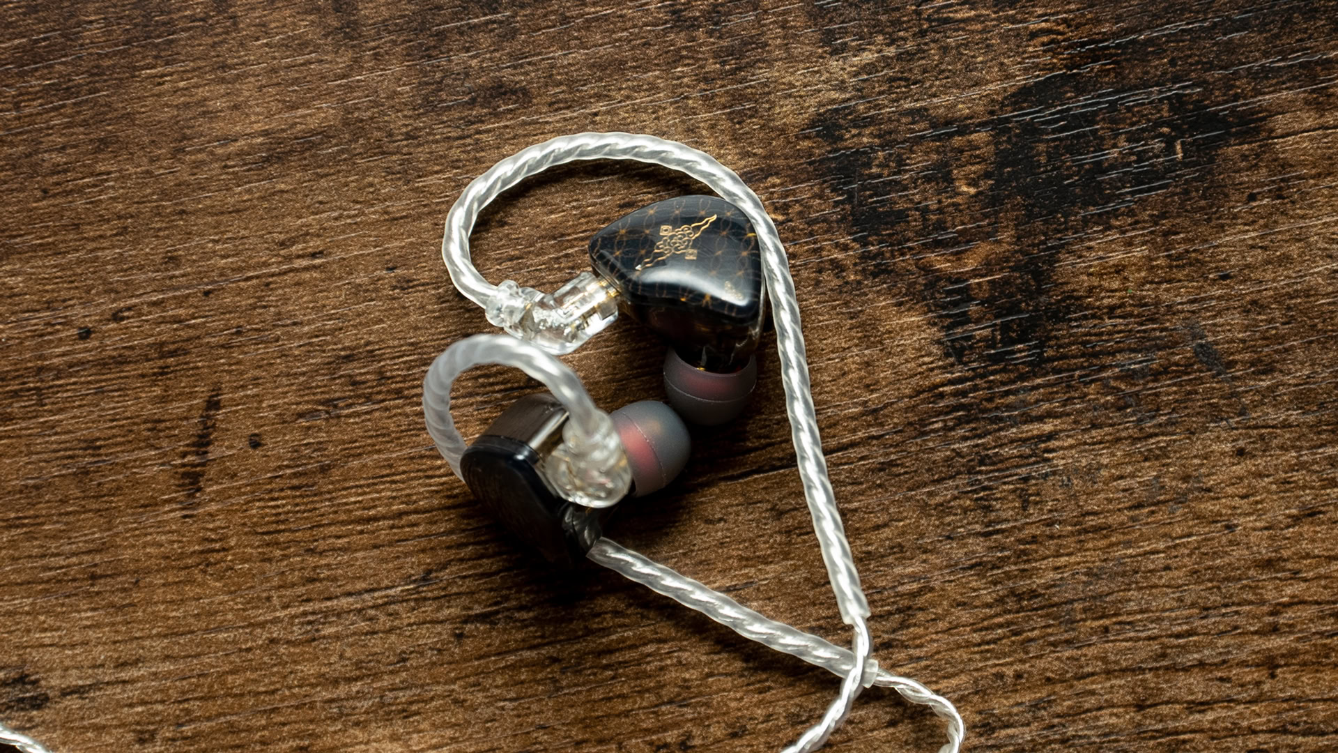 A photo of the Tangzu Wan'er S.G. earbuds on a wooden desk.