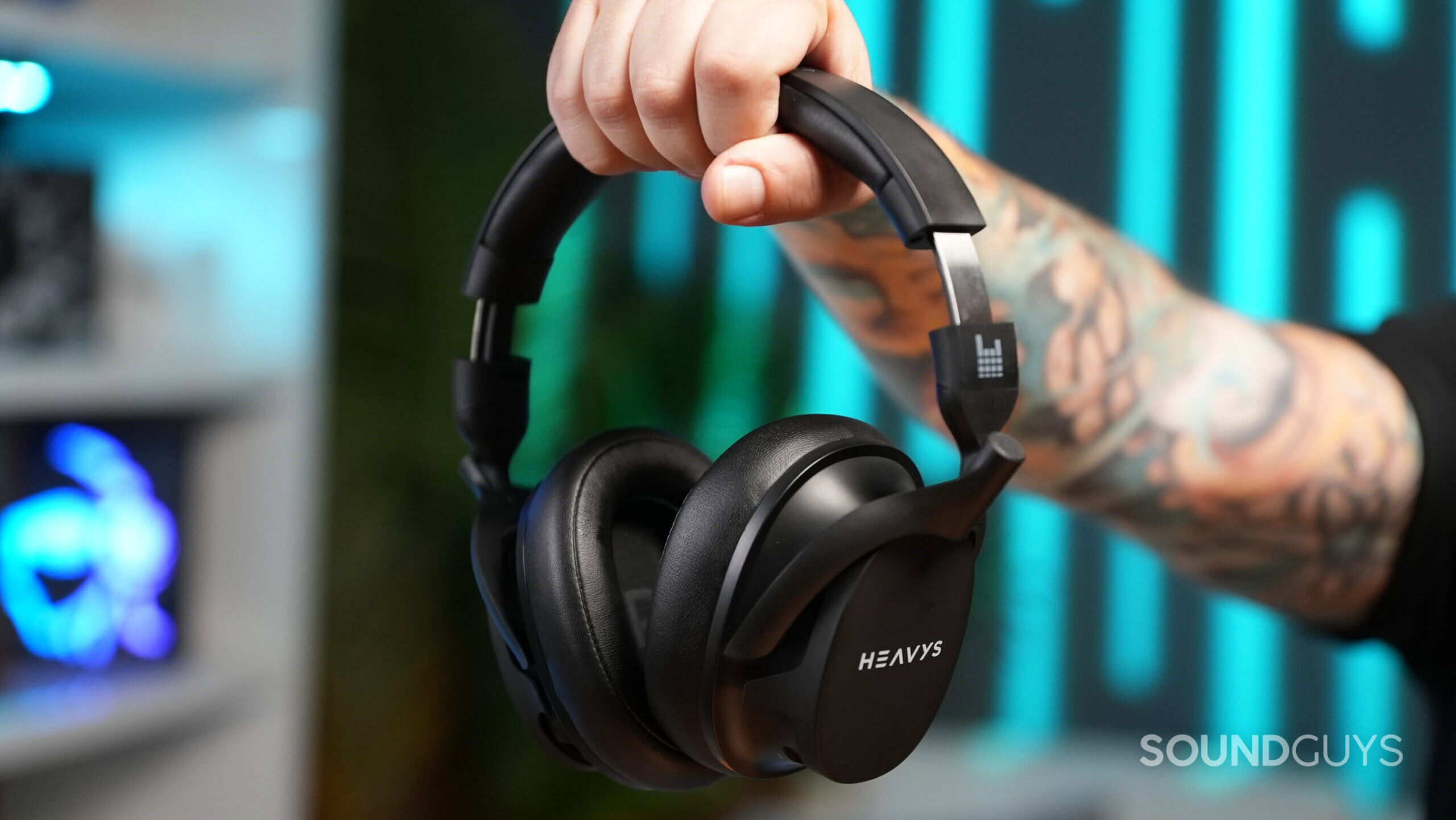 A hand holding the Heavy H1H headphones by the headband.