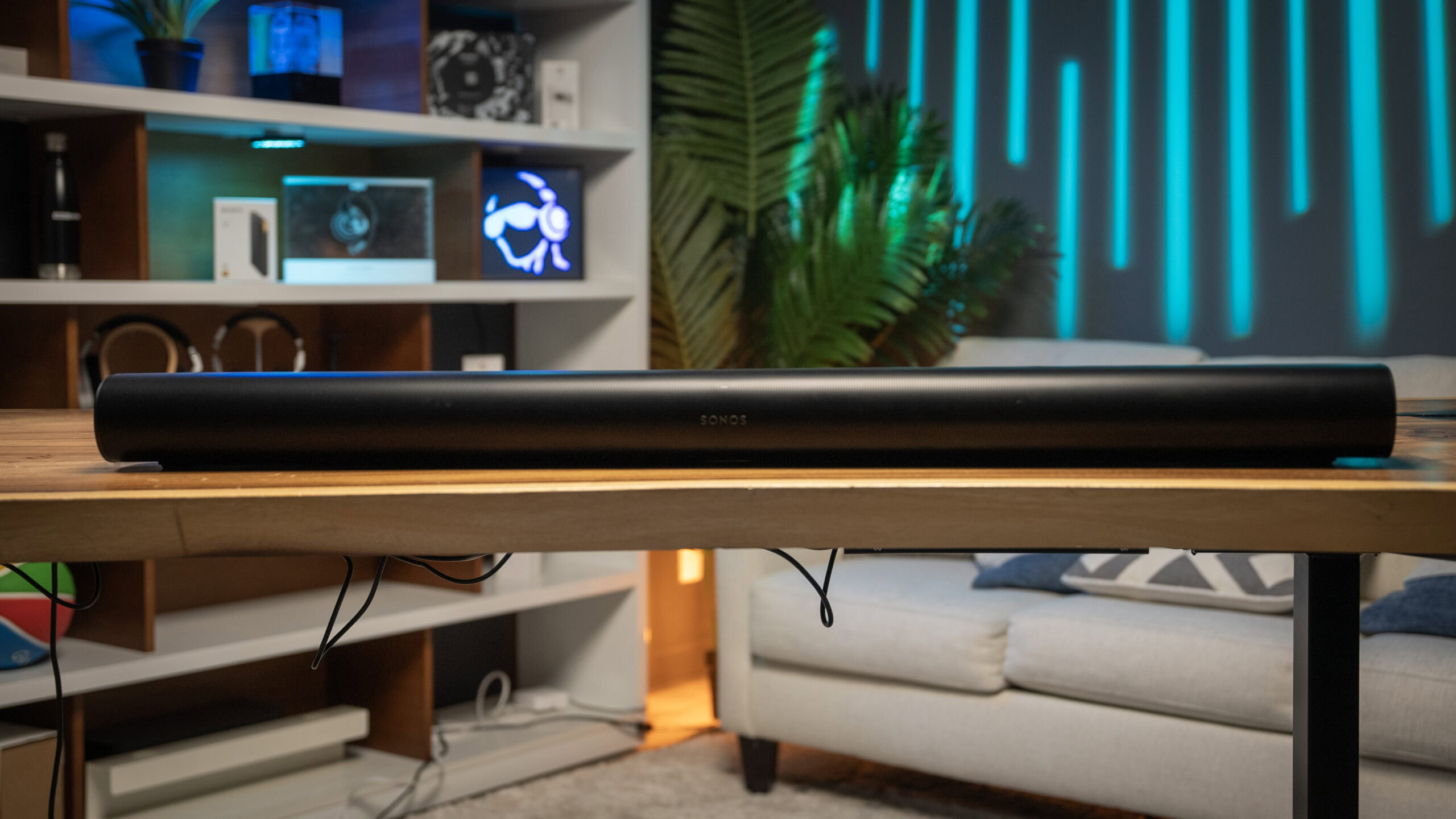 The Sonos Arc soundbar is placed on a wooden table in the middle of a brightly-colored studio setup.